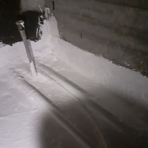 צינורות מתכת עם חומר איטום לבן על קיר בטון