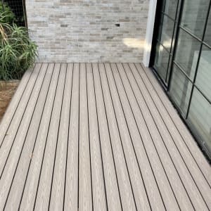 דק עץ בהיר ליד קיר לבנים אפור