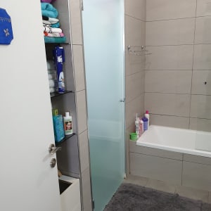 מקלחת עם דלת זכוכית, מגבות ומוצרי טיפוח