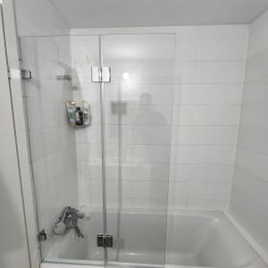 אמבטיה עם דלת זכוכית, ראש מקלחת ומוצרי טיפוח