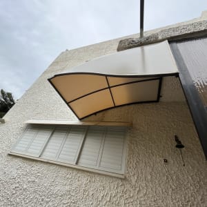 סוכך בד לבן עם מסגרת מתכת על קיר חיצוני