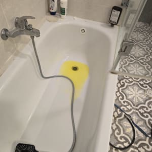 אמבטיה עם מים צהובים, צינור ומקלחת יד