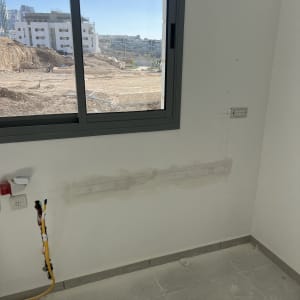 קיר עם שקע חשמל וחוטים חשמליים חשופים