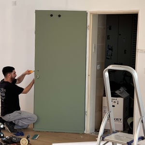 אדם מתקין דלת ירוקה עם כלים וסולם