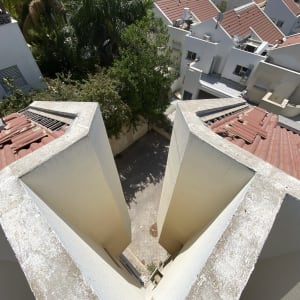 גגות רעפים אדומים עם קולטי שמש ומעקה בטון