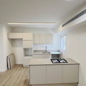 מטבח מודרני עם ארונות לבנים וכיריים על אי