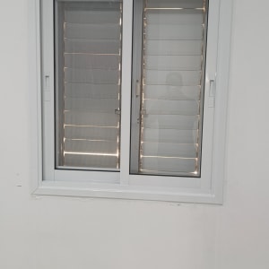 חלון אלומיניום עם תריסים ומזגן על הקיר