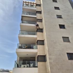 אדם תלוי על חבל צובע קיר חיצוני של בניין