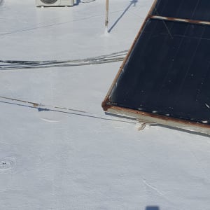 גג אטום בלבן עם קולטי שמש ומזגן