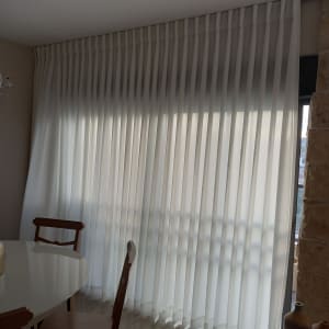 וילון לבן ארוך תלוי על חלון גדול