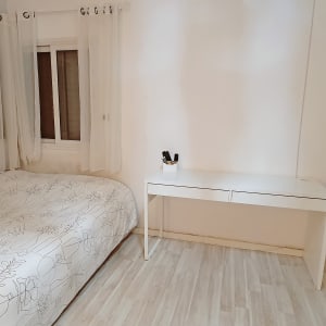 חדר שינה עם מיטה, שולחן לבן וקופסה עם עטים