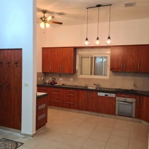 מטבח עם ארונות עץ, כיור ותנור