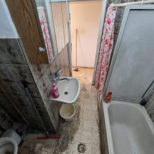 חדר אמבטיה עם כיור, אמבטיה, ודלי על הרצפה