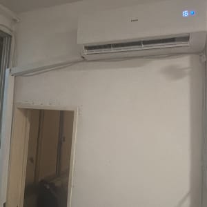 מזגן מותקן על קיר ליד חלון עם סורגים