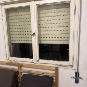 תריסים סגורים על חלון בחדר שינה עם מיטה