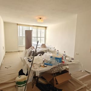 חדר עם ציוד לצביעה, יריעות פלסטיק ומברשות.