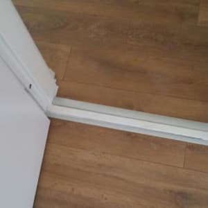 רצפת פרקט חומה עם מסגרת דלת לבנה