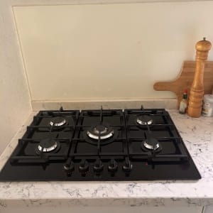 כיריים גז שחורות עם חמישה מבערים וכפתורי שליטה