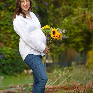 אישה בהריון מחזיקה זר פרחים צבעוני