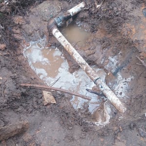 צינור מים שבור באדמה בוצית