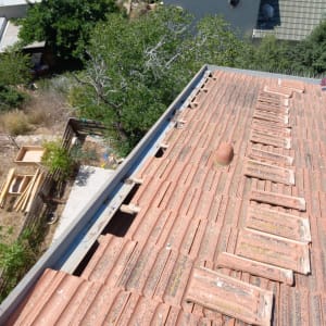 רעפים שבורים על גג רעפים אדום עם פתחי אוורור