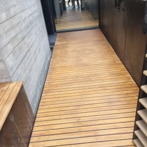 רצפת עץ חיצונית עם קיר בטון וגדר מתכת