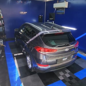 רכב אפור בחדר עם רצפת דמקה כחולה ושחורה