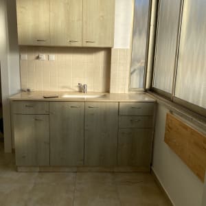 כיור מטבח עם ארונות עץ ומשטח נקי