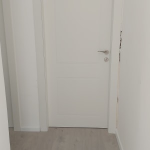 דלת לבנה עם ידית כסופה על רצפת עץ