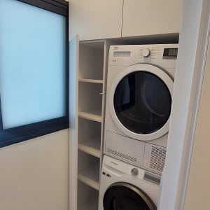 מכונת כביסה ומייבש בארון עם מדפים פתוחים