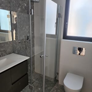 מקלחון זכוכית עם ראש מקלחת עגול ומוט מתכת