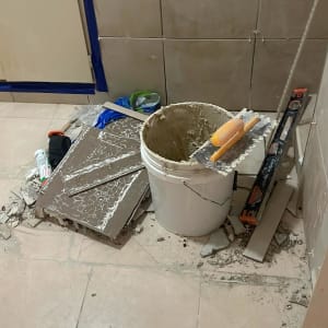 עבודות חיפוי קיר באריחי קרמיקה בתהליך ביצוע עם כלי עבודה