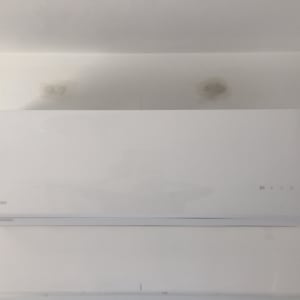 מזגן לבן מותקן על קיר עם כתמי רטיבות