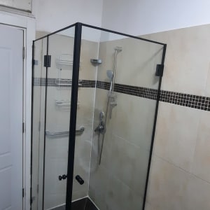 מקלחון זכוכית עם ראש מקלחת ומדף מתכת