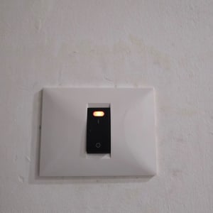 מתג חשמלי על קיר עם אור אדום דולק