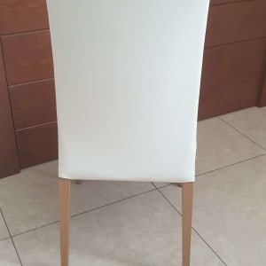 כיסא מרופד בלבן עם רגלי עץ על רצפה מרוצפת