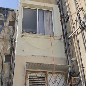 תיקון טיח וצביעת קטע חזית בגובה סביב מסגרת חלון