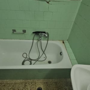 אמבטיה עם אריחים ירוקים וברז מקלחת