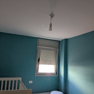 קיר צבוע בכחול עם חלון ומנורה