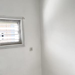 קיר לבן עם חלון קטן ושקע חשמל
