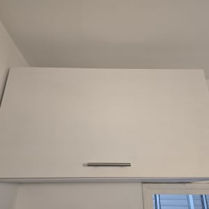 ארון קיר עם ידית מתכת מותקן על קיר לבן