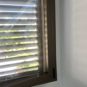 תריסים מותקנים על חלון עם אור שמש חודר