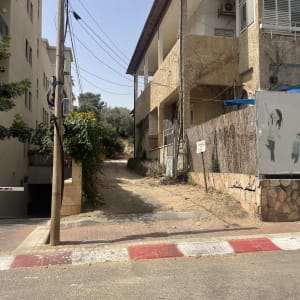 שביל בין בניינים עם עמוד חשמל ועצים