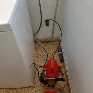 מכונת ניקוי צינורות אדומה ליד מכונת כביסה