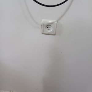 שקע חשמל בקיר עם כבל חשמל תלוי