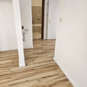 רצפת עץ נקייה עם כיור ודלת לחדר אמבטיה
