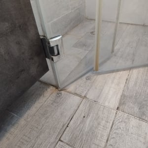 דלת זכוכית למקלחת על רצפת עץ אפורה