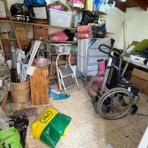 חדר מלא חפצים וציוד, כולל כיסא גלגלים וסולמות