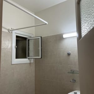 חדר אמבטיה עם חלון פתוח, כיור ומדף זכוכית