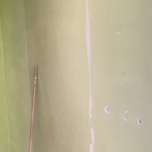 קיר צבוע עם תיקוני טיח ומקל צבע